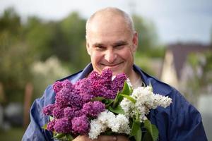 Alten Mann mit ein Strauß von Blumen. brutal grau haarig Mann mit ein schön lila. foto