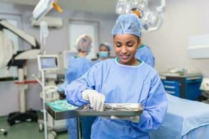 Chirurgin in chirurgischer Uniform, die chirurgische Instrumente im Operationssaal nimmt. junge Ärztin im Operationssaal des Krankenhauses foto