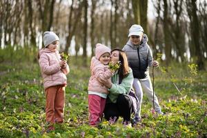 glücklich Mutter Tag. wir Liebe Du, Mama. Mutter mit ein Strauß von Blumen und drei Kinder im Frühling Blühen Wald. foto