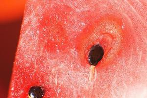 Scheibe von Wassermelone auf Orange Hintergrund Nahansicht. Wassermelone Samen Makro foto