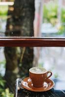 ein Tasse von Matcha Latté mit Latté Kunst in der Nähe von das Fenster foto