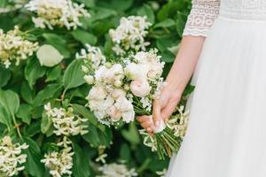 schöner zarter Hochzeitsblumenstrauß in den Händen der Braut foto