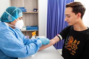 jung weiblich Krankenschwester Sammeln ein Blut Stichprobe von ein männlich geduldig im ein Klinik foto