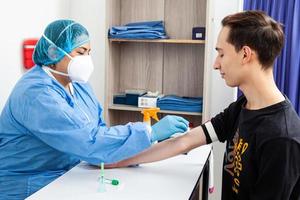 jung weiblich Krankenschwester desinfizieren ein Patienten Arm Vor nehmen ein Blut Stichprobe foto