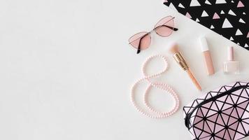 kosmetische Produkte mit Sonnenbrille auf rosa Hintergrund