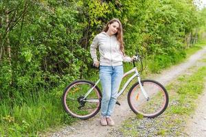 junge frau, die fahrrad im sommerstadtpark draußen fährt. aktive Menschen. Hipster-Mädchen entspannen und Fahrrad fahren foto