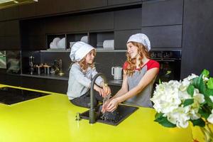 zwei Mädchen mit Koch Hut umarmen und haben Spaß im Küche foto