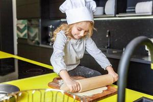 wenig Mädchen vorbereiten Teig, backen hausgemacht Urlaub Apfel Kuchen im Küche foto