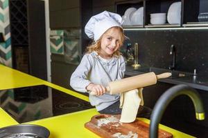 wenig Mädchen vorbereiten Teig, backen hausgemacht Urlaub Apfel Kuchen im Küche foto