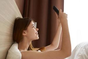 Frau mit Telefon im Bett foto