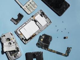 flache Lage zerlegter Telefonteile auf blauem Hintergrund foto