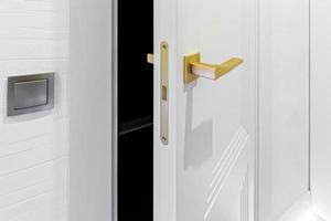 klassisch Stil Weiß Tür. geöffnet Weiß Tür zu das Badezimmer. klassisch Weiß Tür mit golden handhaben. Nahansicht foto