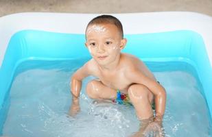 heiß Wetter. Junge spielen mit Wasser glücklich im das Wanne. foto