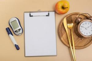 leeren Text Tafel und Glukometer und Besteck mit Alarm Uhr auf Teller eben legen, oben Sicht. spotten oben Diabetes Thema foto