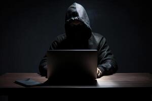 Hacker tragen schwarz Kapuzenpullover mit Laptop Computer während Arbeiten auf dunkel Hintergrund. ai generiert foto