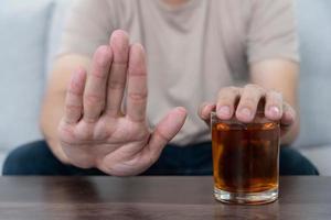 Mann weigert sich sagen Nein und vermeiden zu trinken ein Alkohol Whiskey , anhalten Hand Zeichen männlich, Alkoholismus Behandlung, Alkohol Sucht, Verlassen Schnaps, halt Trinken Alkohol. sich weigern Glas Alkohol, ungesund, ablehnen foto