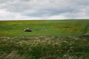 Traktor Fahren auf Bauernhof im Blume Feld durch das Silberstrang Strand im Galway, Irland foto