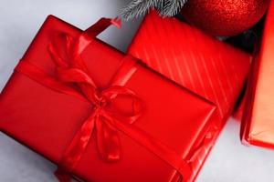 rot Geschenk Kisten mit Bänder und Weihnachten Kugeln auf Weiß Hintergrund. Überraschungen im Kisten eingewickelt im rot Geschenk Papier mit Bogen. Konzept von Ferien und Gruß Karten. foto