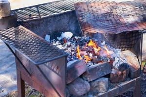 Feuer in einem rostigen Weinlesegrill im Freien mit unscharfem Hintergrund foto