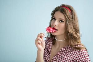 ein schön Mädchen isst ein hell Lutscher. retro Brünette Mädchen mit Süßigkeiten. foto
