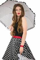 schön retro Mädchen. Frau im ein Rock mit Polka Punkte mit ein Regenschirm. foto