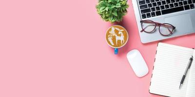 Büro Schreibtisch mit Computer, Stift, Brille, Maus, Notizbuch, Tasse von Kaffee auf Rosa Hintergrund, oben Aussicht mit Kopieren Raum, spotten hoch. foto