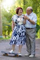 glücklich Alten Paar mit ein Skateboard. gut aussehend Mann und Frau Senior Bürger. Mann und Ehefrau von alt Alter zum ein gehen im das Stadt. foto