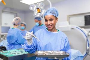 Chirurgin in chirurgischer Uniform, die chirurgische Instrumente im Operationssaal nimmt. junge Ärztin im Operationssaal des Krankenhauses foto