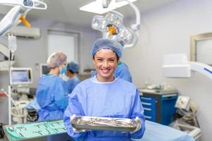 Porträt von der Chirurg Stehen im Betriebs Zimmer, bereit zu Arbeit auf ein geduldig. weiblich medizinisch Arbeiter chirurgisch Uniform im Betrieb Theater. foto