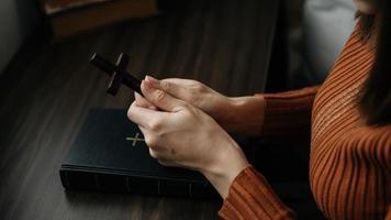 frau, die sitzt und die schriften studiert. das holzkreuz in den händen. christliche bildungskonzepte öffnen die heilige schrift foto