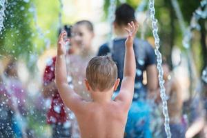 Kinder baden im ein Brunnen. Junge auf ein heiß Tag beim das Stadt Brunnen. foto