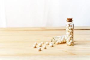 Konzept von homöopathisch Tabletten im Flaschen auf hölzern Tabelle Weiß Hintergrund foto