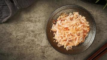 oben Aussicht bonito Flocken oder katsuobushi auf ein Keramik Teller auf ein Holz Hintergrund. eben legen foto