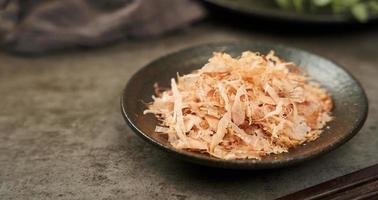 schließen oben bonito Flocken oder katsuobushi auf ein Keramik Teller auf ein Zement Hintergrund foto