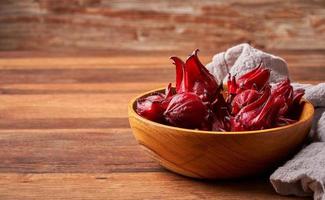 Konzept von hausgemacht frisch rot Roselle Früchte oder Hibiskus Sabdariffa im hölzern Schüssel auf Holz Tabelle Hintergrund foto