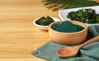 Laminaria oder Seetang Seetang und Spirulina Pulver im Holz Schüssel und Löffel Hintergrund. Spirulina Pulver mit konbu und Alge Essen auf Holz Tabelle Hintergrund. foto