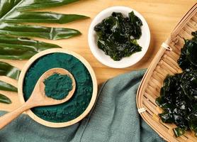 oben Aussicht Laminaria oder Seetang Seetang und Spirulina Pulver im Holz Schüssel und Löffel Hintergrund. eben legen Spirulina Pulver mit konbu und Alge Essen auf Holz Tabelle Hintergrund foto