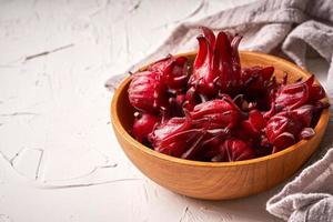 Konzept von hausgemacht frisch rot Roselle Früchte oder Hibiskus Sabdariffa im hölzern Schüssel auf Weiß Tabelle Hintergrund foto