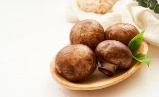 braun Champignon Taste Pilz und Grün Blatt im Holz Schüssel auf Weiß Tabelle Hintergrund. Stapel von braun Champignon Taste Pilz foto