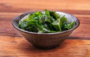 Laminaria Seetang Seetang im schwarz Schüssel auf hölzern Tisch. miyeok muchim. Koreanisch Seetang Salat foto