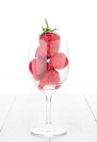 frisch Erdbeere im Wein Glas isoliert auf Weiß Holz foto