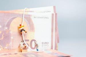 Miniaturmenschen, Kletterer klettert auf eine Euro-Banknote, Geschäftskonzept. foto
