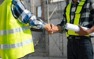 Ingenieur und Auftragnehmer beitreten Hände nach Unterzeichnung Vertrag, sie sind haben ein modern Gebäude Projekt zusammen. erfolgreich Zusammenarbeit foto