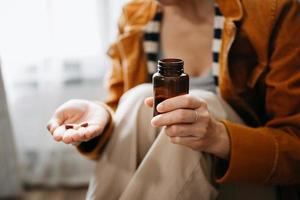 Frauenhand, die eine Flasche mit Pillen in der Hand hält, um die von seinem Arzt verschriebenen Medikamente einzunehmen foto