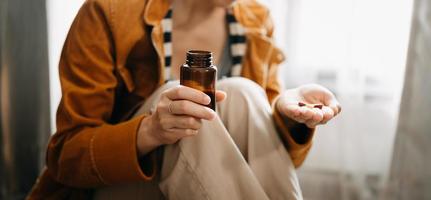 Frauenhand, die eine Flasche mit Pillen in der Hand hält, um die von seinem Arzt verschriebenen Medikamente einzunehmen foto