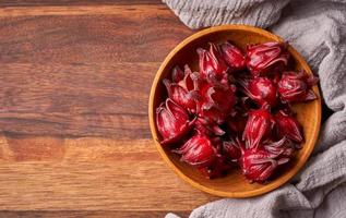 Konzept von hausgemacht frisch rot Roselle Früchte oder Hibiskus Sabdariffa im hölzern Schüssel auf Holz Tabelle Hintergrund. oben Aussicht foto