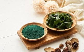 Laminaria oder Seetang Seetang und Spirulina Pulver im Holz Teller Hintergrund. Spirulina Pulver mit konbu und Alge Essen auf Weiß Tabelle Hintergrund. foto