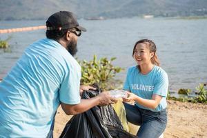 glücklich Gruppe von jung Freiwillige Reinigung Plastik beim Fluss Strand. Umwelt und ökologisch Pflege, Erde Tag Konzept foto