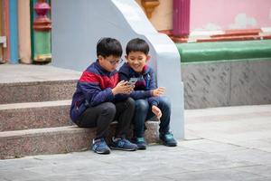 asiatisch Kinder draußen mit ein Smartphone. foto