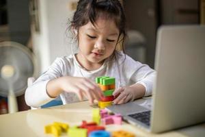 asiatisches Mädchen, das Alphabete online lernt, glückliches Mädchen, das online mit Laptop zu Hause lernt. neue Normalität. Covid-19-Coronavirus. soziale Distanzierung. zu Hause bleiben foto